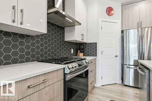 Kitchen with stainless steel appliances, light stone countertops, backsplash, light wood-type flooring, and modern cabinets - 8018 Kiriak Link, Edmonton, AB - Indoor Photo Showing Kitchen With Upgraded Kitchen