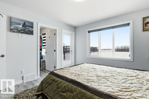 Bedroom with a spacious closet, light wood-style floors, and a textured ceiling - 8018 Kiriak Link, Edmonton, AB - Indoor Photo Showing Bedroom