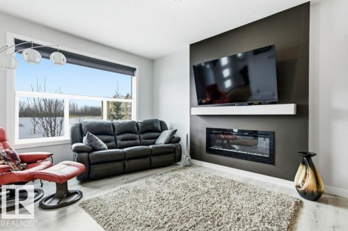 Living area featuring a glass covered fireplace and light wood-style floors - 8018 Kiriak Link, Edmonton, AB - Indoor Photo Showing Living Room With Fireplace