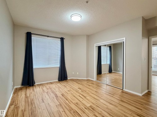 Unfurnished bedroom featuring a textured ceiling, light wood-type flooring, and a closet - 115 11039 83 Avenue, Edmonton, AB - Indoor Photo Showing Other Room