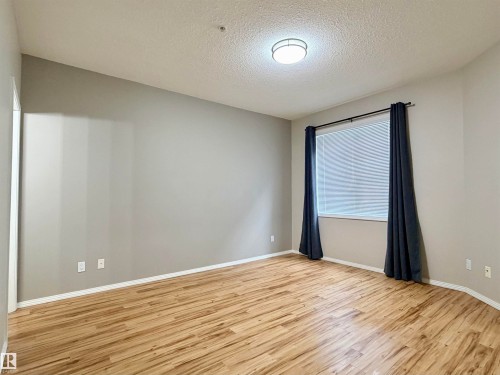 Empty room featuring a textured ceiling and light wood-style flooring - 115 11039 83 Avenue, Edmonton, AB - Indoor Photo Showing Other Room