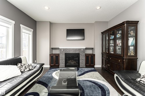Living area featuring dark wood-type flooring, a tiled fireplace, and recessed lighting - 115 57 Street, Edmonton, AB - Indoor Photo Showing Living Room With Fireplace