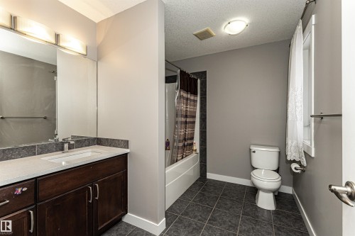 Bathroom with vanity, a textured ceiling, shower / tub combo with curtain, and dark tile patterned floors - 115 57 Street, Edmonton, AB - Indoor Photo Showing Bathroom