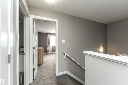 Corridor featuring an upstairs landing, dark colored carpet, and a textured ceiling - 115 57 Street, Edmonton, AB - Indoor Photo Showing Other Room