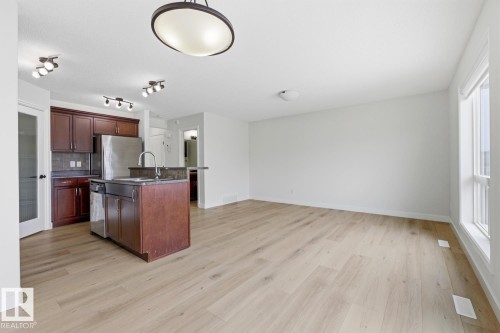 Kitchen featuring dark countertops, stainless steel appliances, an island with sink, and light wood finished floors - 73 Keystone Crescent Crescent, Leduc, AB - Indoor Photo Showing Kitchen