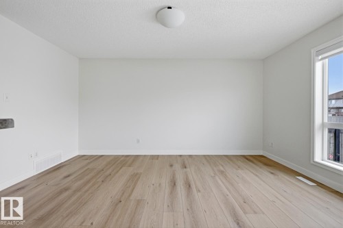 Spare room featuring light wood finished floors and a textured ceiling - 73 Keystone Crescent Crescent, Leduc, AB - Indoor Photo Showing Other Room With Fireplace