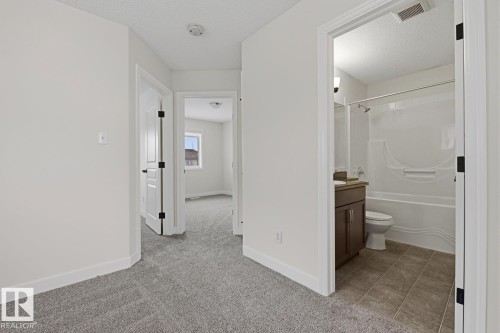 Full bath featuring vanity, light colored carpet, a textured ceiling, and bathtub / shower combination - 73 Keystone Crescent Crescent, Leduc, AB - Indoor