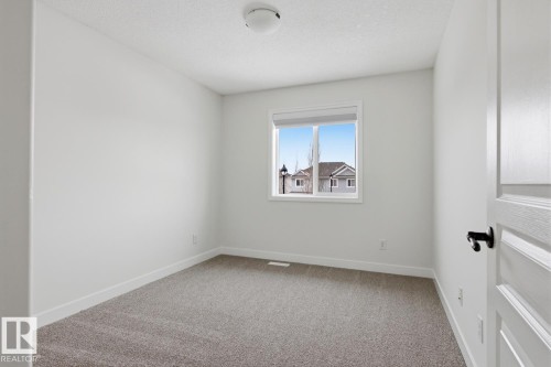Empty room featuring light carpet and a textured ceiling - 73 Keystone Crescent Crescent, Leduc, AB - Indoor Photo Showing Other Room