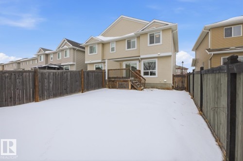 Snow covered rear of property featuring a fenced backyard, a residential view, and a deck - 73 Keystone Crescent Crescent, Leduc, AB - Outdoor With Exterior