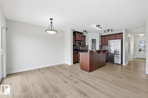 Kitchen featuring a kitchen bar, stainless steel appliances, an island with sink, and light wood-type flooring - 73 Keystone Crescent Crescent, Leduc, AB - Indoor Photo Showing Kitchen
