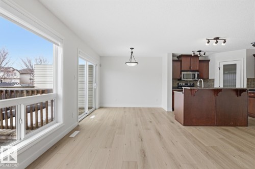 Kitchen with a breakfast bar, stainless steel appliances, tasteful backsplash, pendant lighting, and light wood-style flooring - 73 Keystone Crescent Crescent, Leduc, AB - Indoor Photo Showing Kitchen