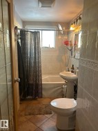 Bathroom featuring tile walls, shower / tub combo with curtain, and light tile patterned floors - 