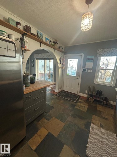 Foyer entrance with a textured ceiling, arched walkways, stone tile flooring, and crown molding - 11406 96 Street, Edmonton, AB - Indoor Photo Showing Other Room