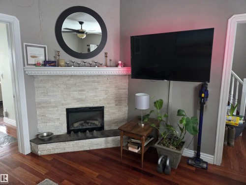 Living room featuring dark wood-style floors, a fireplace, and a ceiling fan - 11406 96 Street, Edmonton, AB - Indoor Photo Showing Living Room With Fireplace