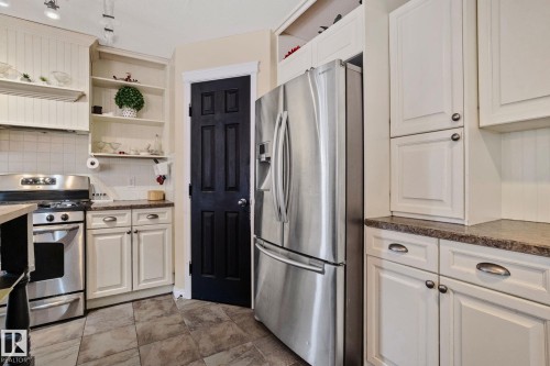 Kitchen featuring stainless steel appliances, open shelves, white cabinets, and decorative backsplash - 502 Westerra Boulevard, Stony Plain, AB - Indoor Photo Showing Kitchen With Stainless Steel Kitchen