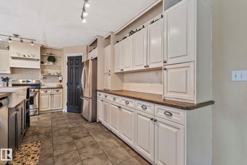 Kitchen with stainless steel appliances, open shelves, backsplash, two tone color scheme, and dark stone countertops - 502 Westerra Boulevard, Stony Plain, AB - Indoor Photo Showing Kitchen With Stainless Steel Kitchen