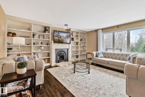 Living area with a fireplace, dark wood-style floors, and built in shelves - 502 Westerra Boulevard, Stony Plain, AB - Indoor Photo Showing Living Room With Fireplace