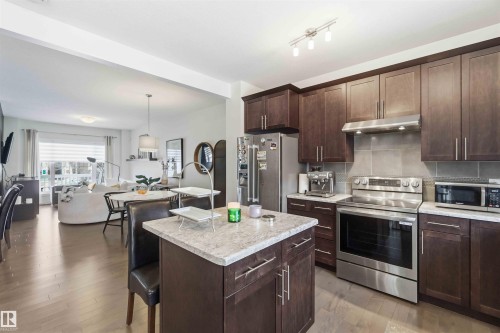 Kitchen with stainless steel appliances, open floor plan, a kitchen bar, a kitchen island, and dark wood finish cabinets - 2331 71 Street, Edmonton, AB - Indoor Photo Showing Kitchen With Stainless Steel Kitchen