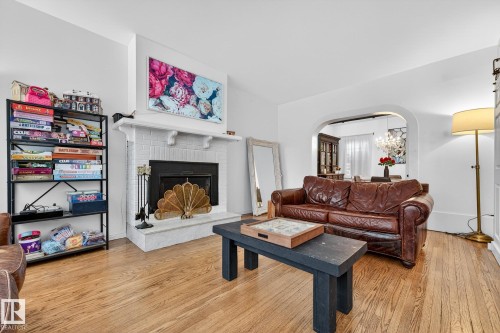 Living room with arched walkways, light wood-style flooring, and a fireplace - 10523 127 Street, Edmonton, AB - Indoor Photo Showing Living Room With Fireplace