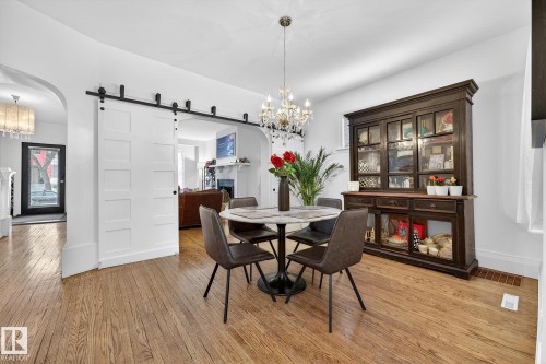 Dining area featuring a barn door, a chandelier, arched walkways, and light wood-type flooring - 10523 127 Street, Edmonton, AB - Indoor Photo Showing Dining Room