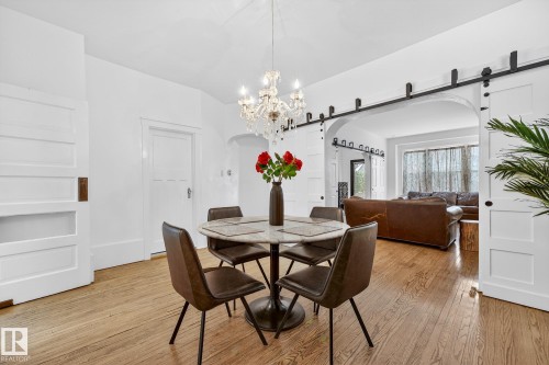 Dining room featuring arched walkways, a barn door, light wood-style floors, and hanging lights - 10523 127 Street, Edmonton, AB - Indoor Photo Showing Dining Room