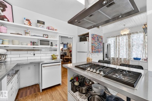 Kitchen with extractor fan, stainless steel countertops, light wood finished floors, stainless steel appliances, and white cabinets - 10523 127 Street, Edmonton, AB - Indoor Photo Showing Kitchen