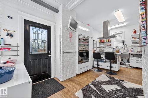 Kitchen featuring a kitchen breakfast bar, light wood-style floors, open shelves, island range hood, and white cabinets - 10523 127 Street, Edmonton, AB - Indoor Photo Showing Other Room