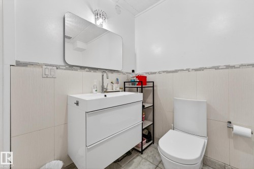 Bathroom with vanity, wainscoting, tile walls, and light tile patterned flooring - 10523 127 Street, Edmonton, AB - Indoor Photo Showing Bathroom