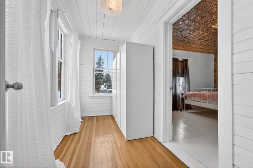 Corridor with light wood finished floors and wood walls - 10523 127 Street, Edmonton, AB - Indoor Photo Showing Other Room