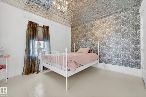 Bedroom featuring wallpapered walls, an ornate ceiling, light wood-type flooring, hanging lights, and an accent wall - 10523 127 Street, Edmonton, AB - Indoor Photo Showing Bedroom
