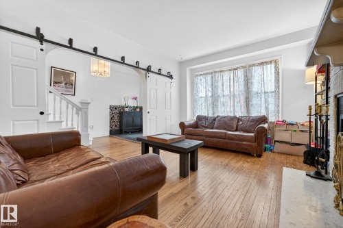 Living area with a barn door, a fireplace with raised hearth, and light wood-type flooring - 10523 127 Street, Edmonton, AB - Indoor Photo Showing Living Room
