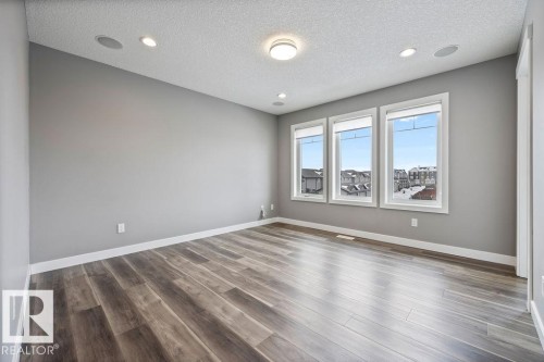 Empty room with a textured ceiling, dark wood-type flooring, and recessed lighting - 7515 178 Avenue, Edmonton, AB - Indoor Photo Showing Other Room