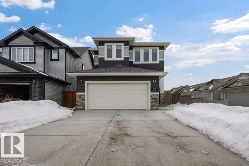 View of front of house with stone siding, driveway, and a garage - 7515 178 Avenue, Edmonton, AB - Outdoor With Facade