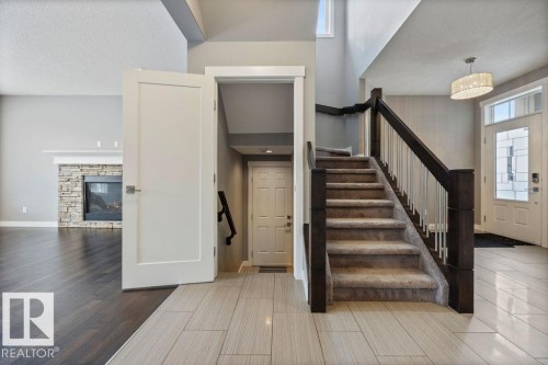 Stairs with wood tiled floors, a stone fireplace, and a high textured ceiling - 7515 178 Avenue, Edmonton, AB - Indoor Photo Showing Other Room With Fireplace