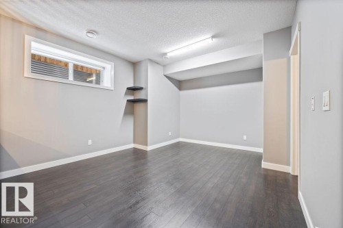 Below grade area with a textured ceiling and dark wood-style flooring - 7515 178 Avenue, Edmonton, AB - Indoor Photo Showing Other Room