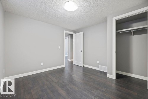 Unfurnished bedroom featuring a textured ceiling, dark wood finished floors, and a closet - 7515 178 Avenue, Edmonton, AB - Indoor Photo Showing Other Room