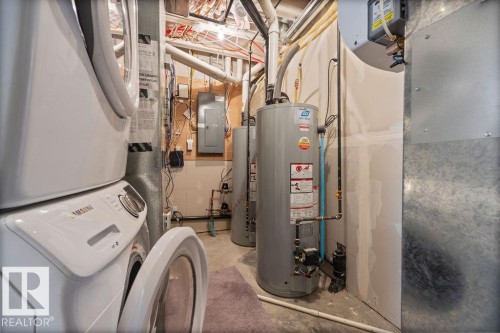 Utility room with electric panel, gas water heater, stacked washer / drying machine, and heating unit - 7515 178 Avenue, Edmonton, AB - Indoor Photo Showing Basement