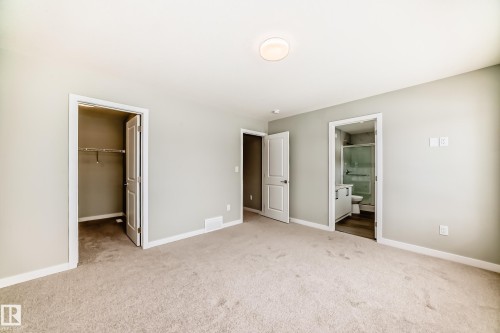Unfurnished bedroom with a walk in closet, carpet floors, and ensuite bathroom - 3323 Roy Brown Way, Edmonton, AB - Indoor