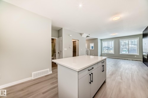 Kitchen featuring a kitchen island, light wood-style floors, light countertops, and open floor plan - 3323 Roy Brown Way, Edmonton, AB - Indoor