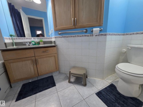 Full bath with vanity, wainscoting, tile walls, and light tile patterned floors - 6731 162 Ave, Edmonton, AB - Indoor Photo Showing Bathroom
