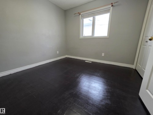 Unfurnished bedroom featuring baseboards and dark wood-style flooring - 6731 162 Ave, Edmonton, AB - Indoor Photo Showing Other Room