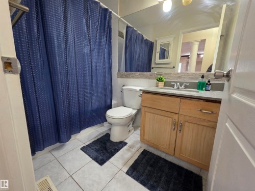 Full bathroom featuring vanity, shower / bath combo with shower curtain, backsplash, and light tile patterned floors - 6731 162 Ave, Edmonton, AB - Indoor Photo Showing Bathroom