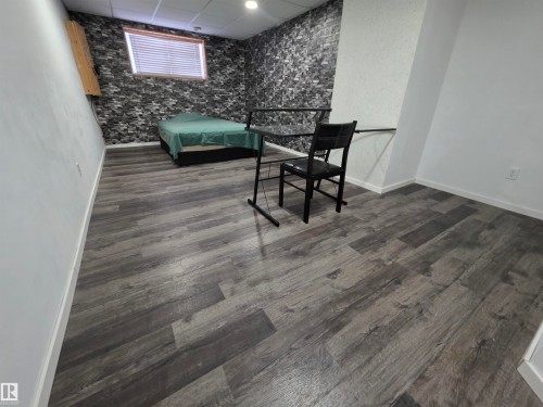 Bedroom featuring a paneled ceiling, an accent wall, and dark wood finished floors - 6731 162 Ave, Edmonton, AB - Indoor Photo Showing Other Room
