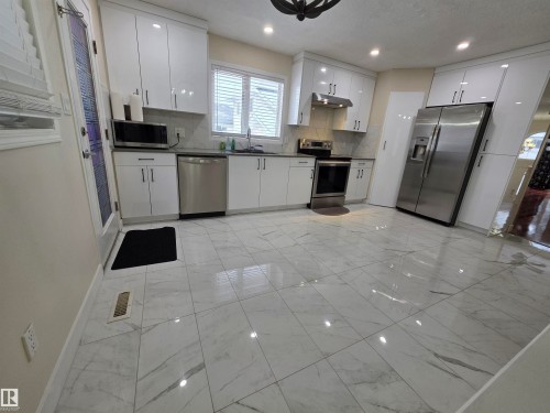 Kitchen featuring stainless steel appliances, white cabinetry, dark countertops, tasteful backsplash, and recessed lighting - 6731 162 Ave, Edmonton, AB - Indoor Photo Showing Kitchen