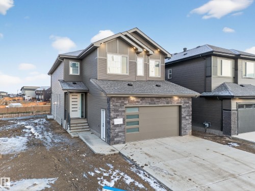 View of front of house with stone siding, driveway, an attached garage, and board and batten siding - 2010 Collip Crescent Sw, Edmonton, AB - Outdoor