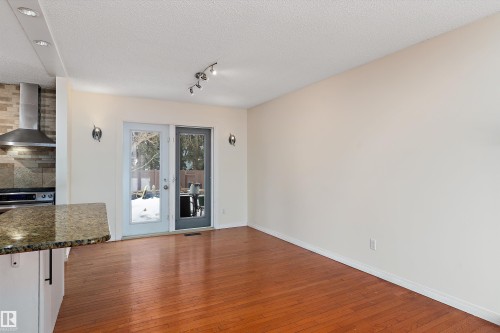 Unfurnished dining area featuring dark wood finished floors and a textured ceiling - 115 Walker Road, Edmonton, AB - Indoor Photo Showing Other Room