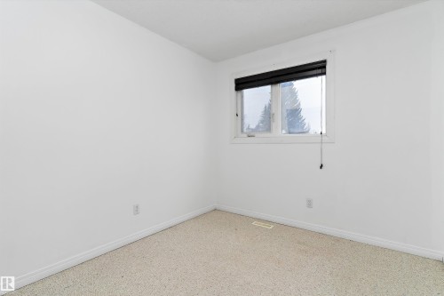 Empty room featuring baseboards and speckle patterned floor - 115 Walker Road, Edmonton, AB - Indoor Photo Showing Other Room
