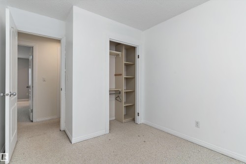 Unfurnished bedroom with a textured ceiling and a walk in closet - 115 Walker Road, Edmonton, AB - Indoor Photo Showing Other Room
