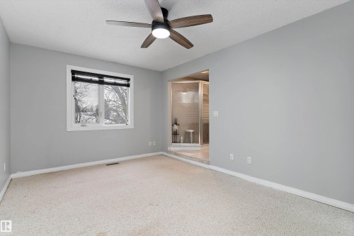 Unfurnished room featuring ceiling fan, a textured ceiling, and dark speckled floor - 115 Walker Road, Edmonton, AB - Indoor Photo Showing Other Room