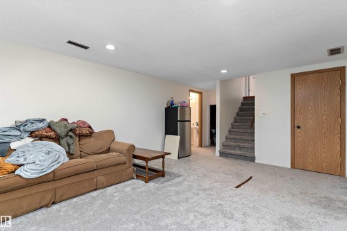 Living room featuring light colored carpet, recessed lighting, and a textured ceiling - 115 Walker Road, Edmonton, AB - Indoor